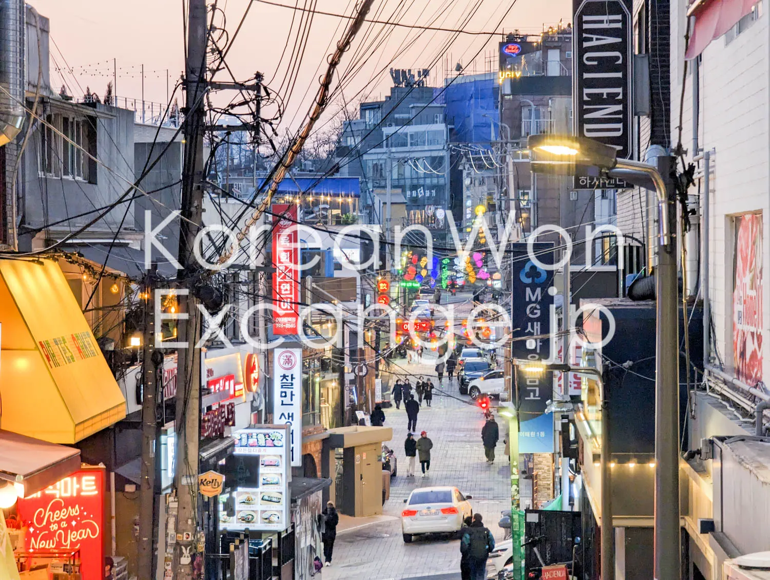 ソウルの繁華街、夕方の細い路地。看板と電線が密集している。