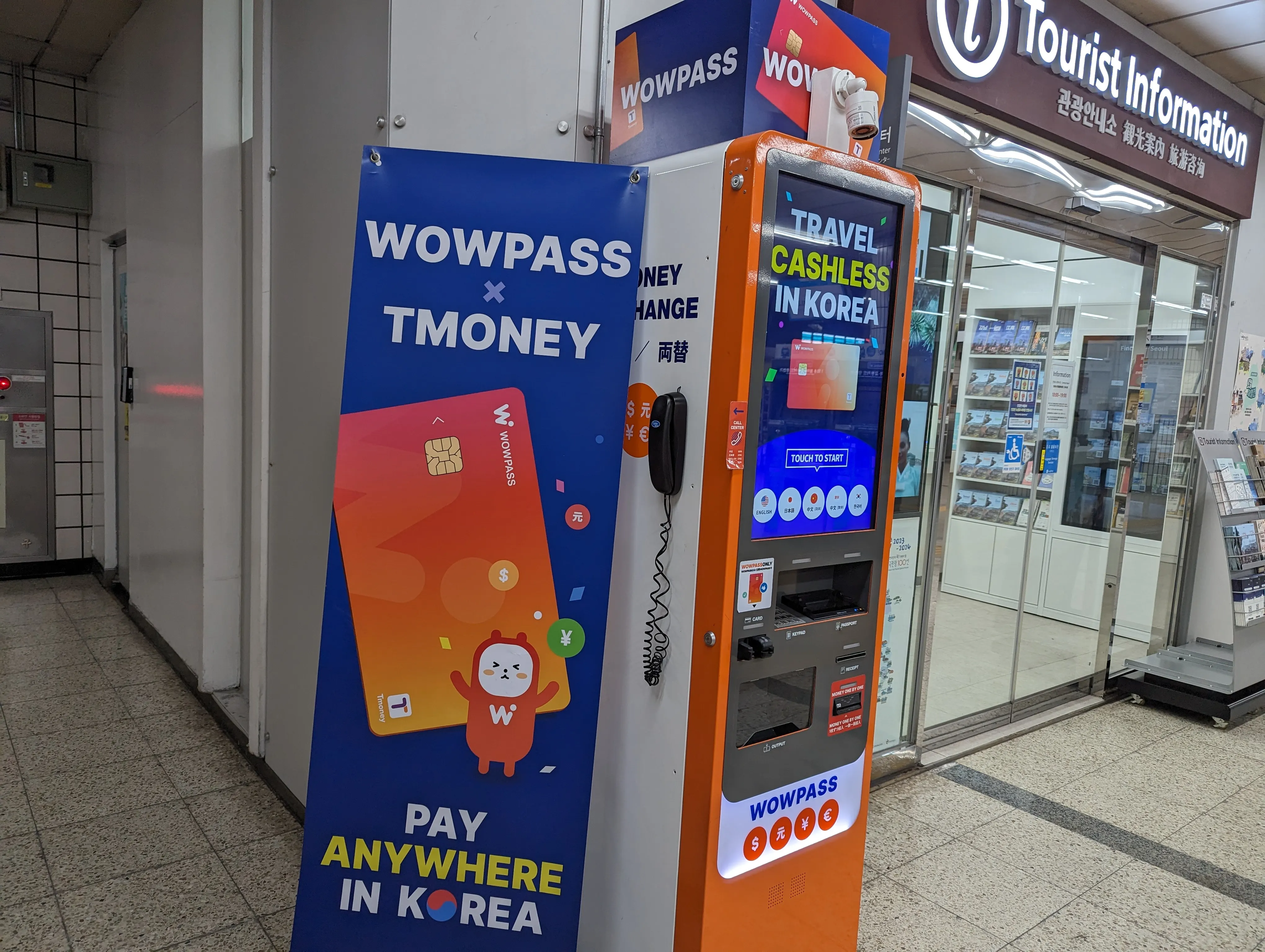 WOWPASS と TMONEY の専用機械。『TRAVEL CASHLESS IN KOREA』のオレンジ筐体と、隣接の WOWPASS × TMONEY 案内パネル。